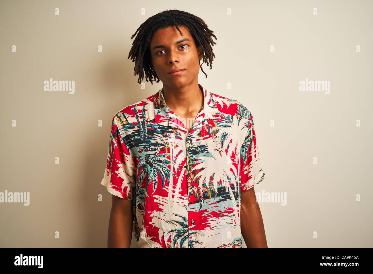 Afro man with dreadlocks on vacation wearing summer shirt over isolated ...