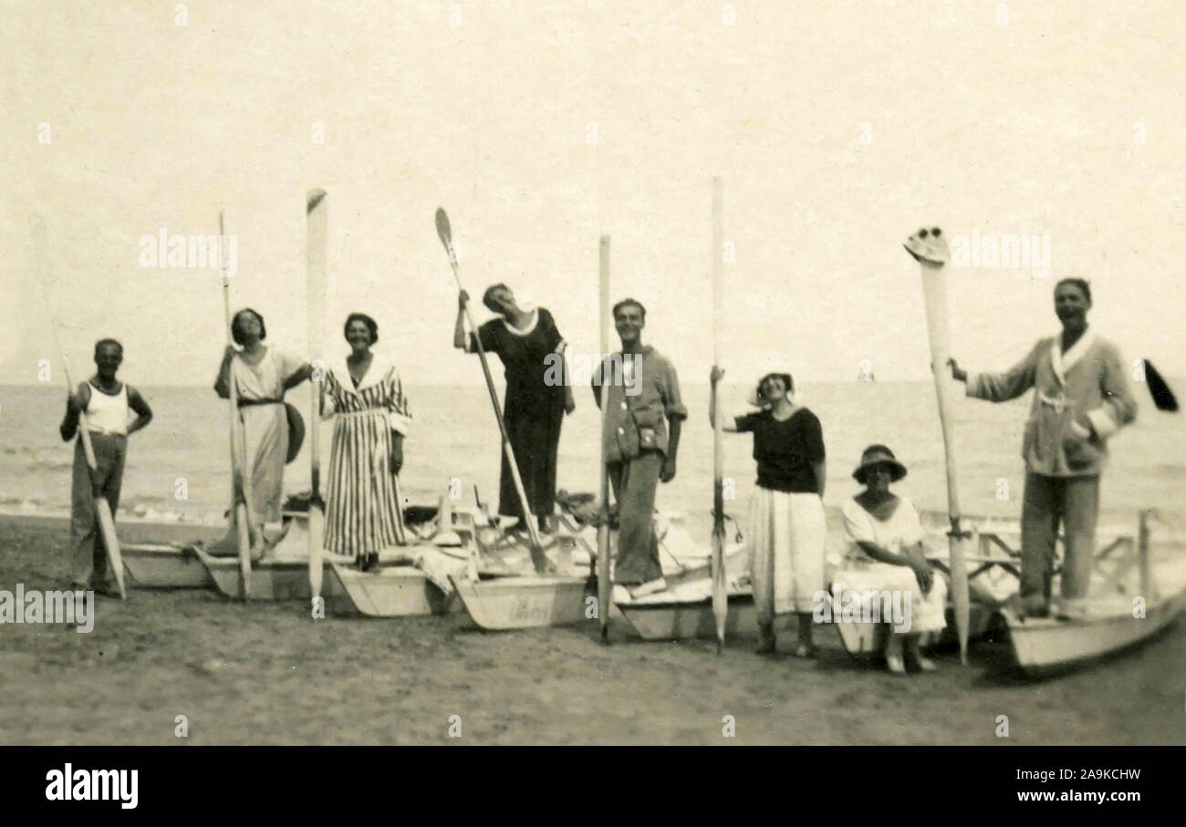 Group at the beach with oars raised, Italy Stock Photo