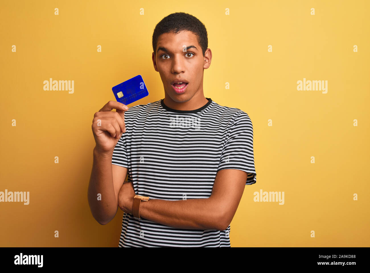 Young handsome arab man holding credit card standing over isolated ...