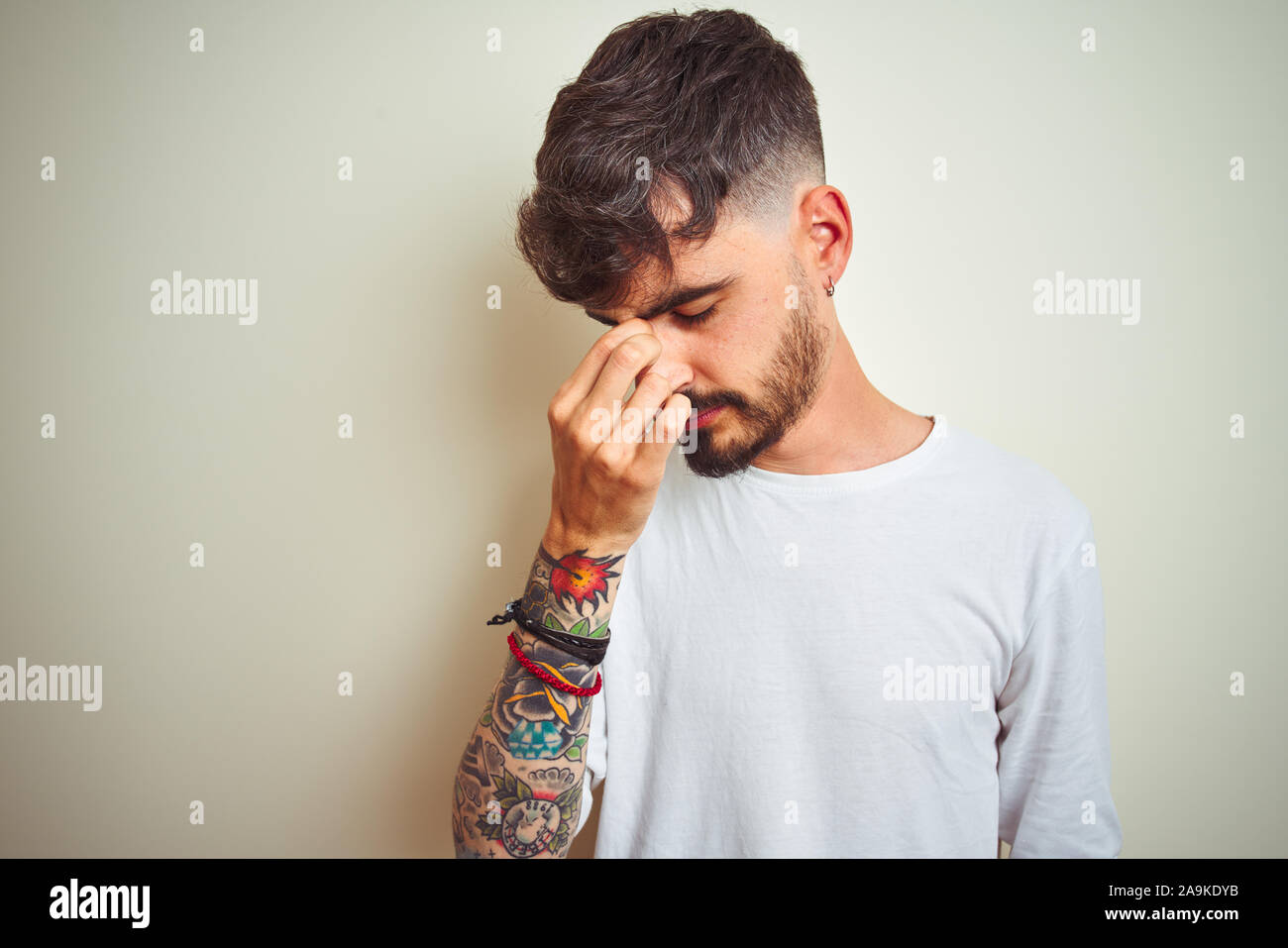Young man with tattoo wearing tshirt standing over isolated white