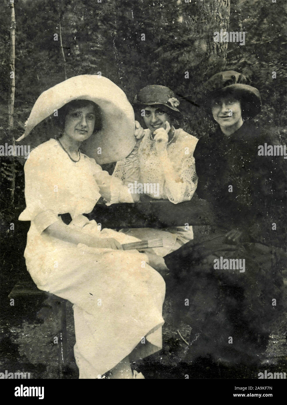 Three women with large hats and dresses of the beginning of the XX century Stock Photo