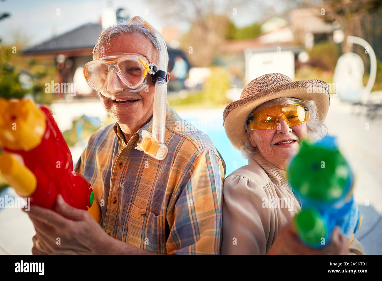 Senior crazy man and woman have fun playing with  water gun. Stock Photo