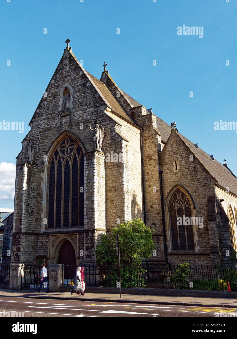 Two Muslim women passing Roman Catholic Church of St Mary & St Michael in Commercial Road, Whitechapel, London, UK Stock Photo