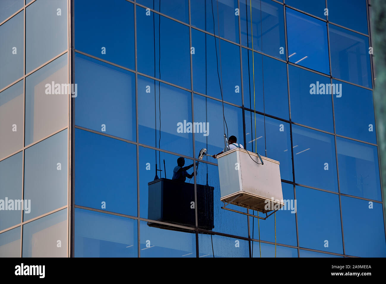 Worker cleaning the windows in a modern glass building, Pamplona Spain Stock Photo