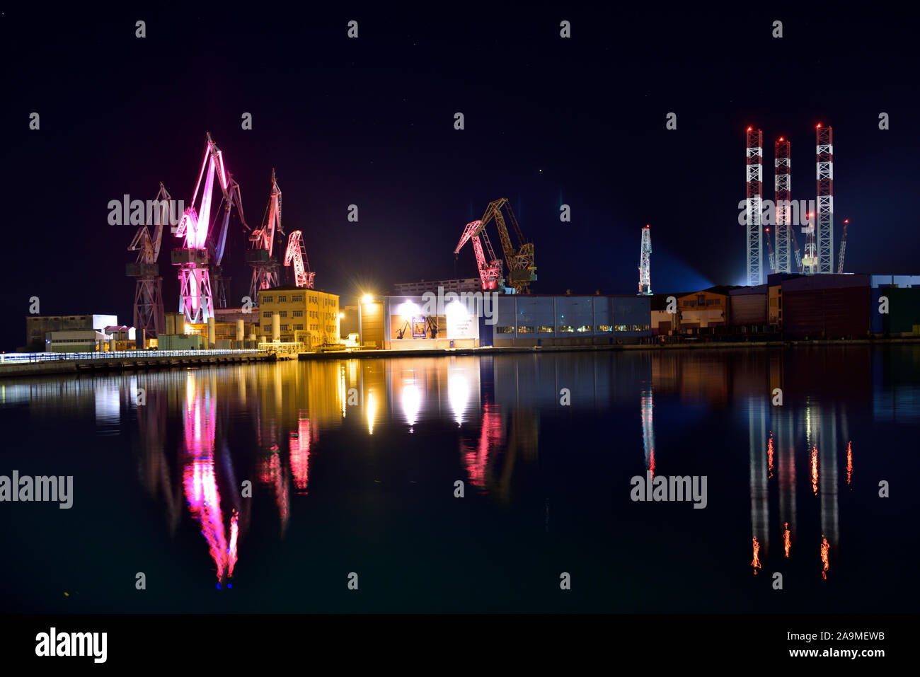 Night time view of colourful lights on shipyard cranes in Pula harbour, Croatia Stock Photo