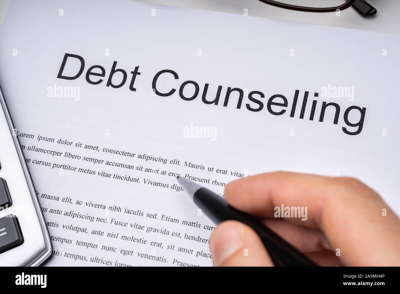 Close-up Of A Person Signing Debt Counseling Form On Office Desk Stock Photo