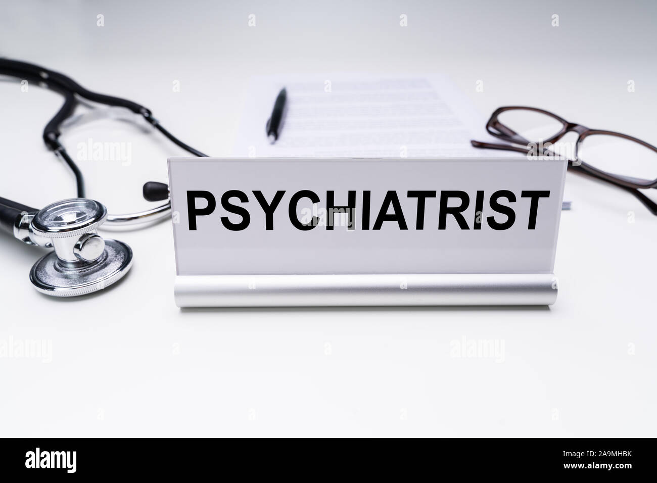 Psychiatrist Job Title On Nameplate Over Desk With Spectacles And