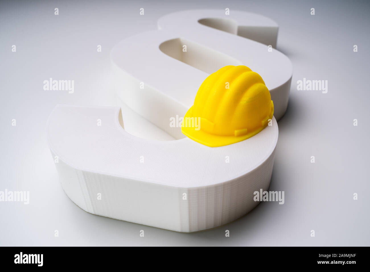 Elevated View Of Yellow Hard Hat Model And White Paragraph Symbol On White Surface Stock Photo