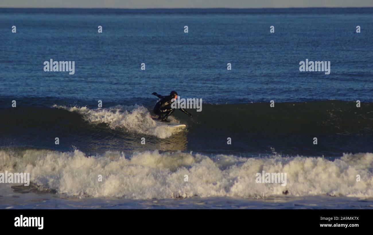 Lone Surfer Riding a Clean Wave in the Golden Light of a Winters Evening. North Sea, Aberdeen Beach, Scotland, UK. Stock Photo