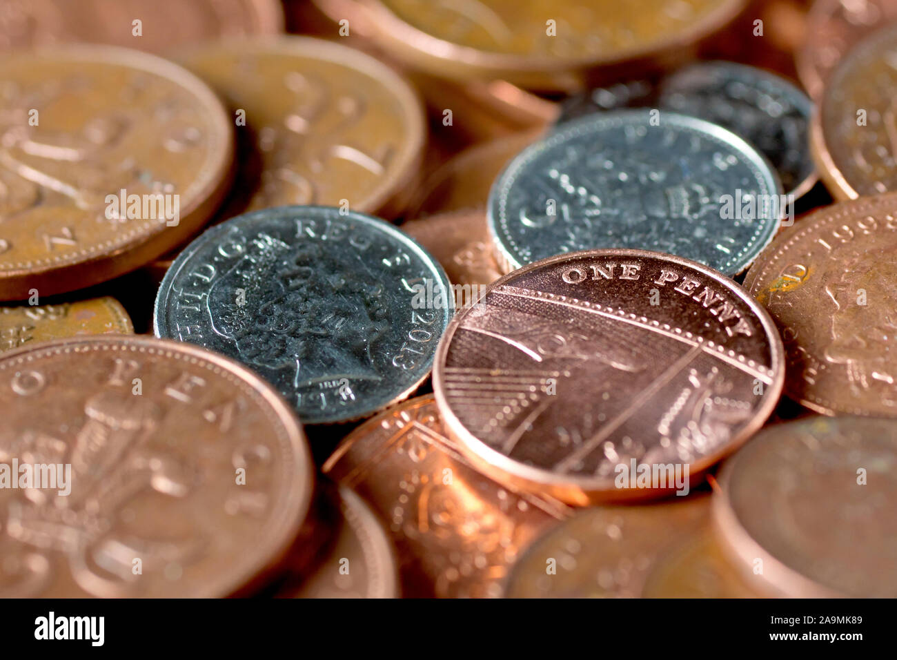 A selection of the lowest denomination coins in circulation in the UK, focusing on a single penny with low depth of field. Stock Photo
