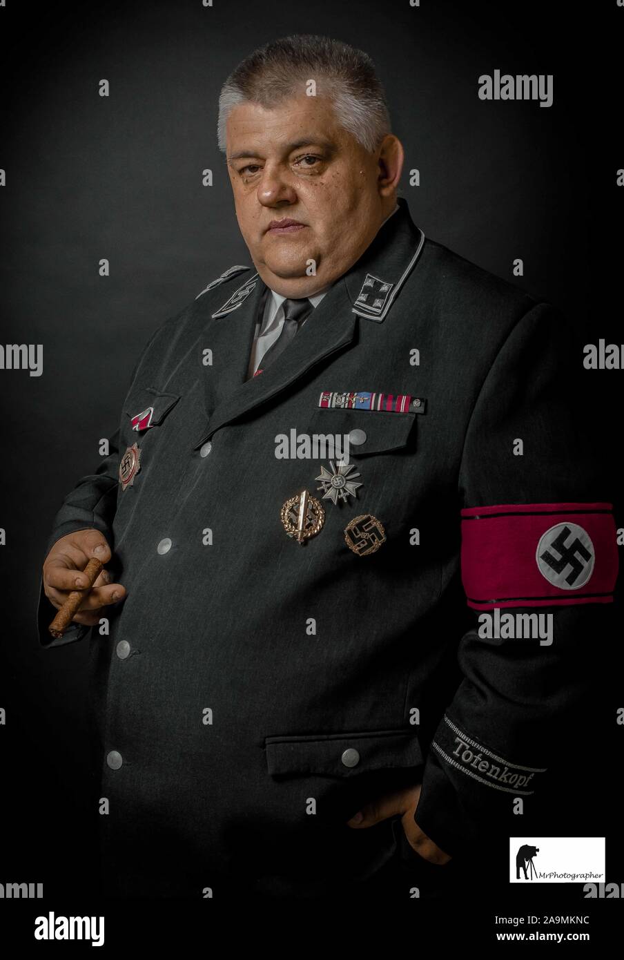 man wearing gestapo uniform smoking a cigar Stock Photo