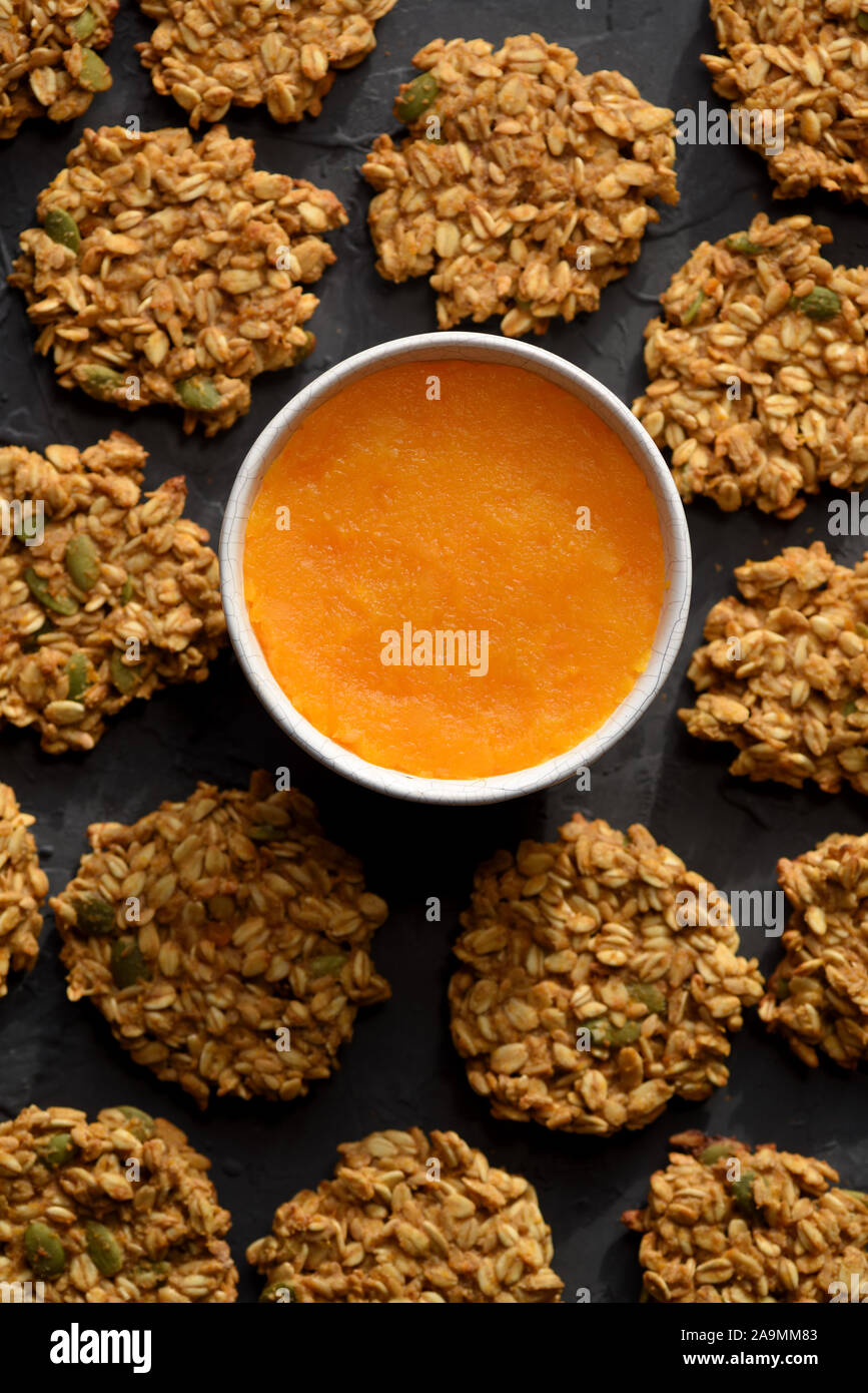 Healthy vegeterian food. Gluten free homemade pumpkin oatmeal breakfast cookies with seeds and pumpkin puree on black background top view Stock Photo
