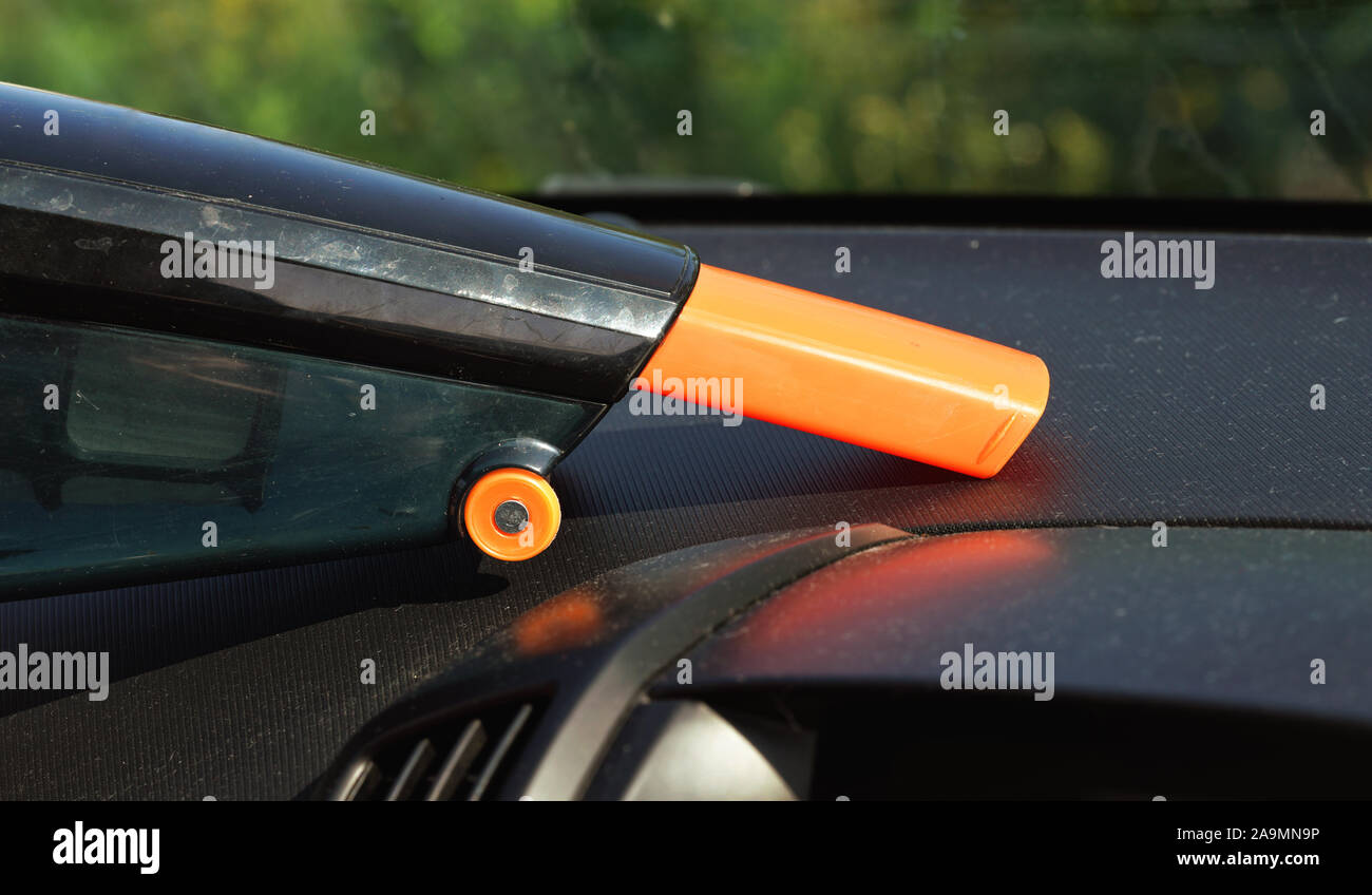 Car interior cleaned from dust with small orange portable vacuum cleaner, closeup on dusty dashboard Stock Photo