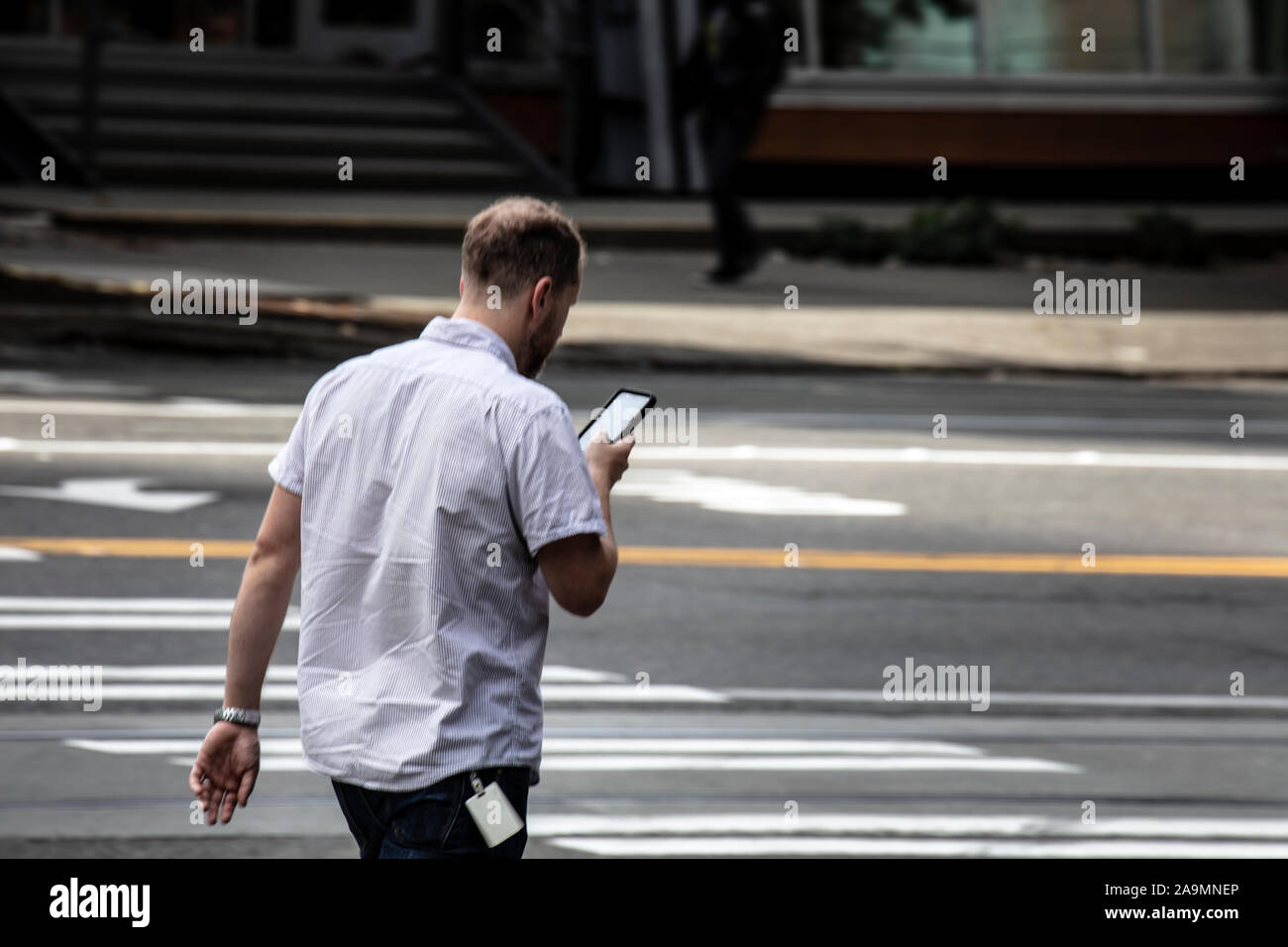 WA17340-00...WASHINGTON - Man walking in Seattle while looking at his cell phone. Stock Photo