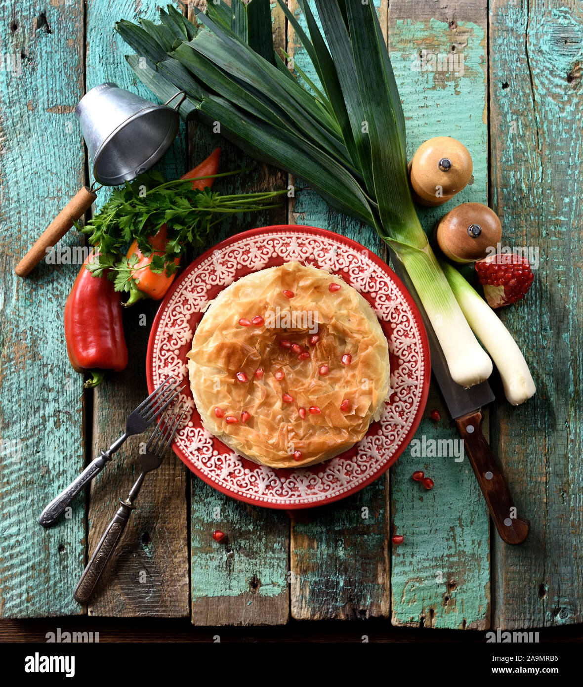 Healthy food. Homemade phyllo pastry pie with raw peppers, leek and pomegranate seeds on wooden background top view copy space overhead view Stock Photo