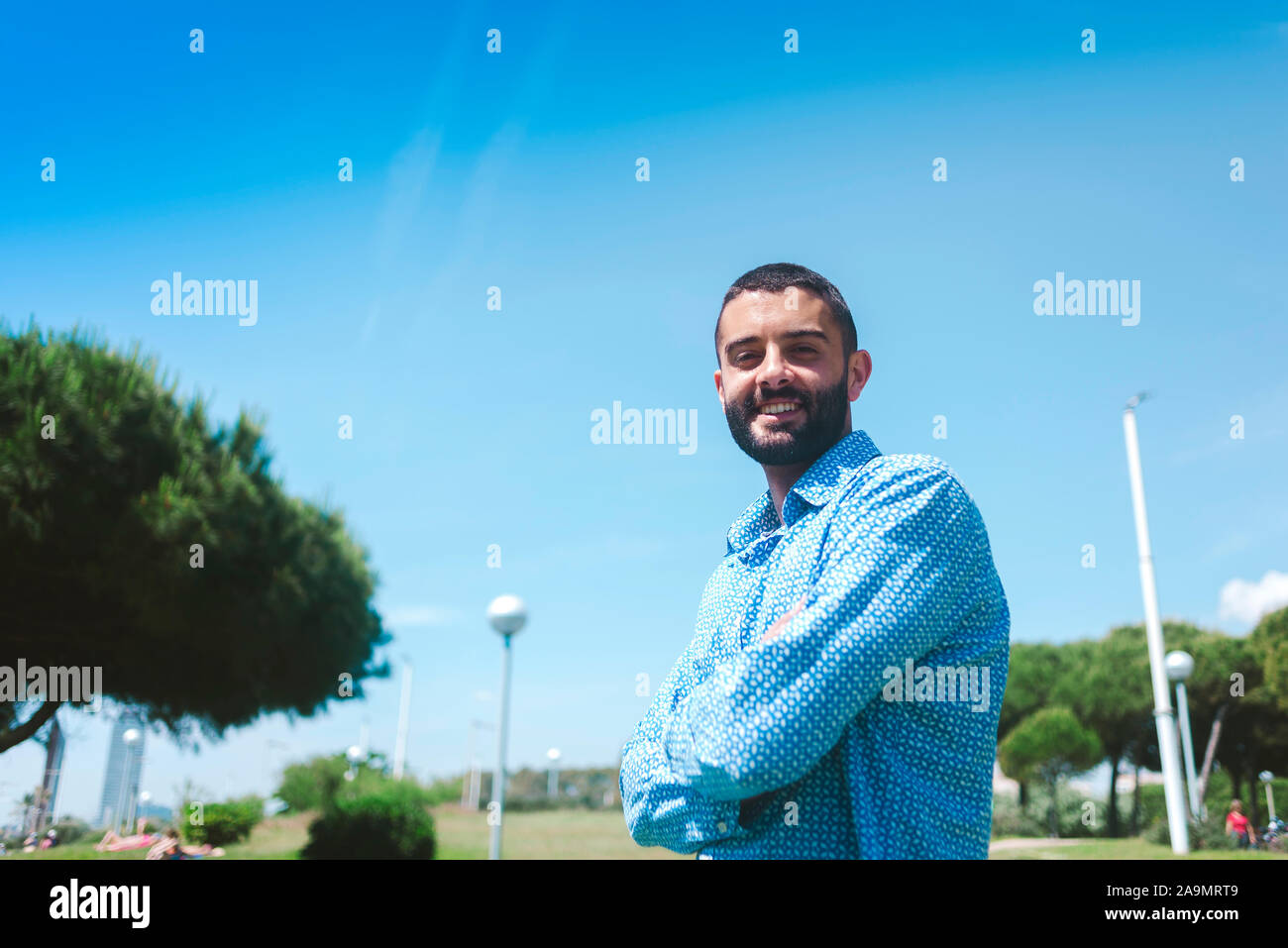 Young man smiling and standing with arms crossed Stock Photo
