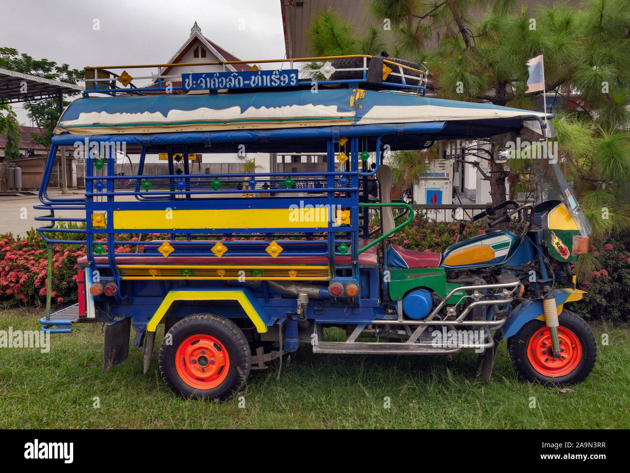 A colourful Tuk Tuk in the street in the picturesque World Heritage Listed city of Luang Prabang in Laos. South East Asia. Popular transportation Stock Photo