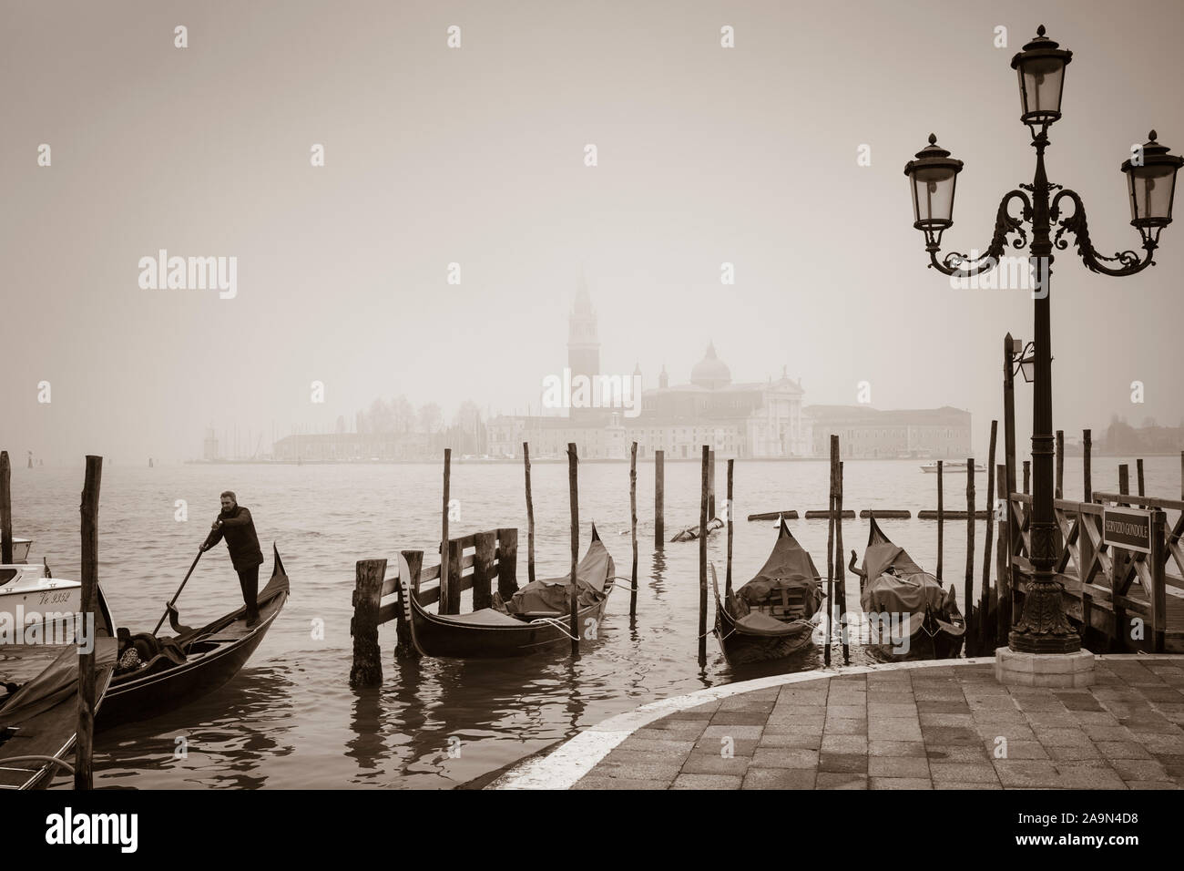 VENICE, ITALY - December 23, 2012. Venice gondola scene in winter with mist on the lagoon. Romantic, retro sepia toned image Stock Photo