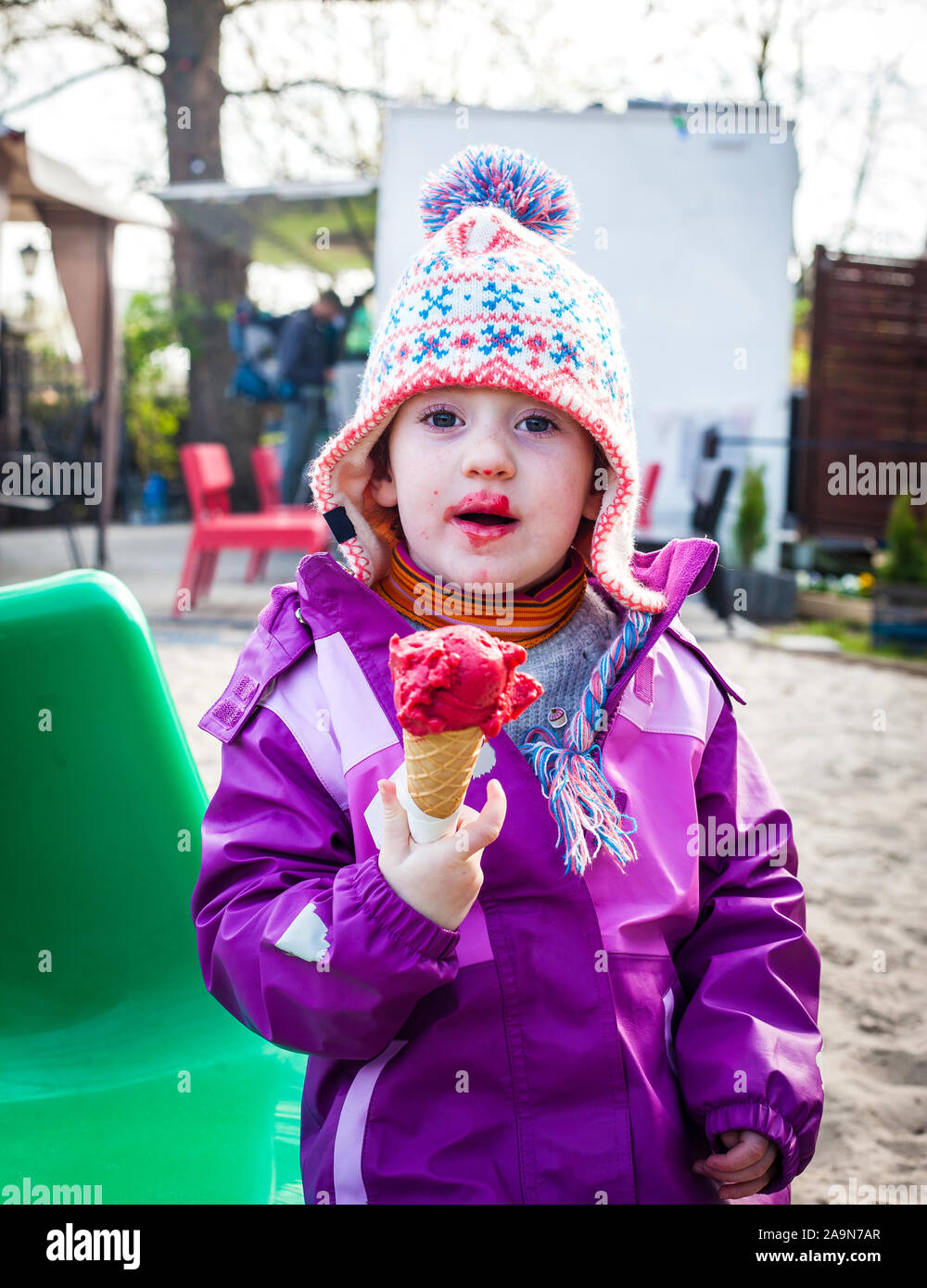 Funny toddler girl eats red berry icecream on a winter day Stock Photo