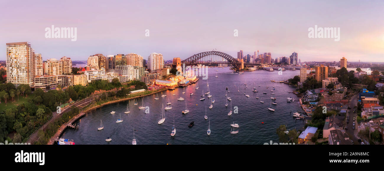 Lavender bay on Sydney Harbour off North shore in view of The Rocks and major Sydney city landmarks in wide aerial panorama at sunset with bright illu Stock Photo