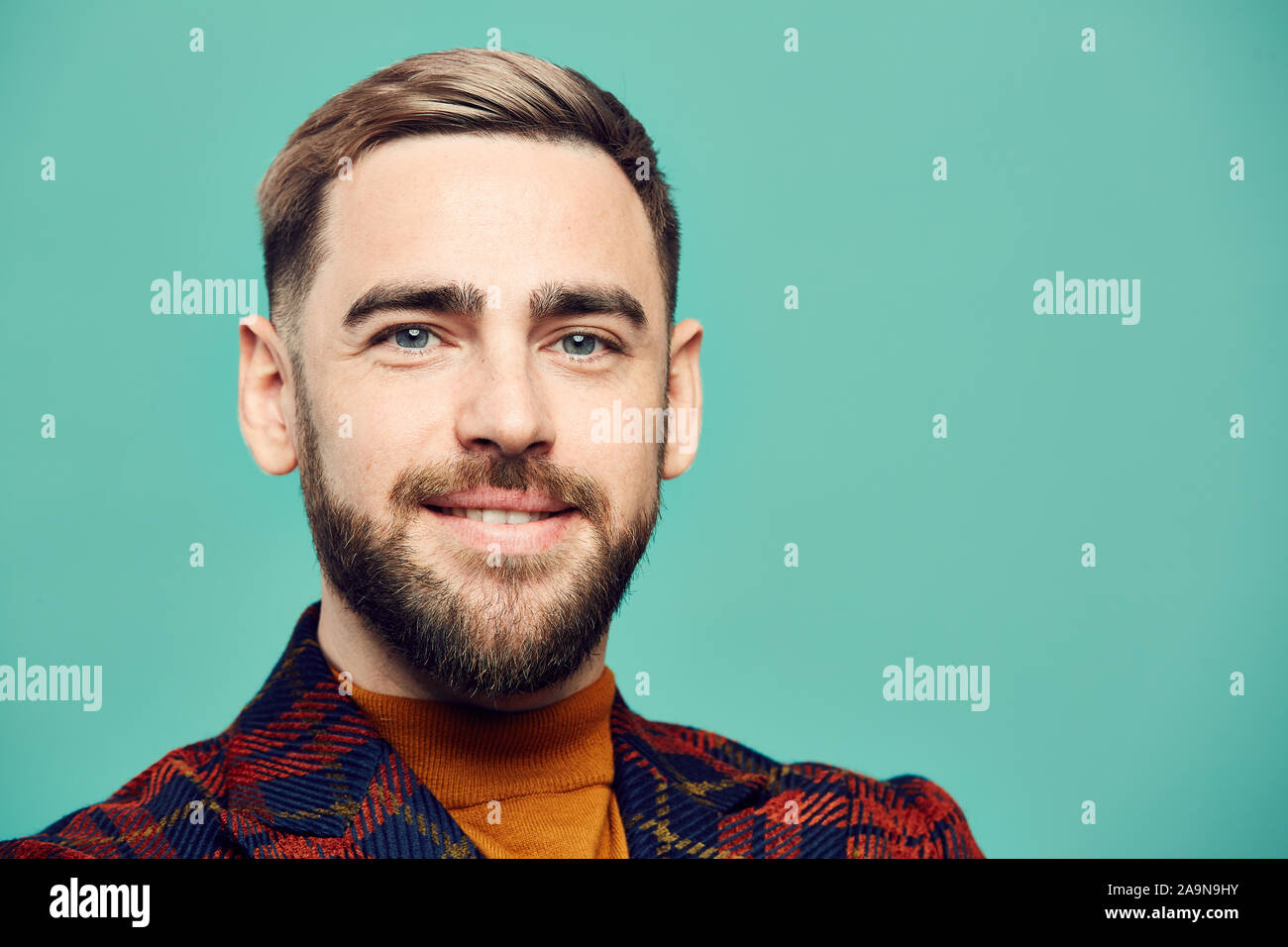 Head and shoulders portrait of bearded adult man smiling at camera