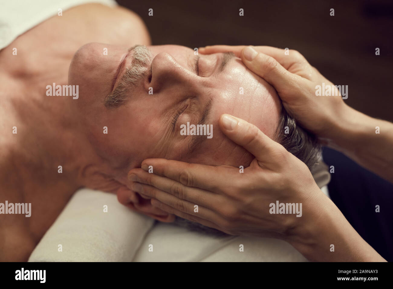 High angle close up of handsome senior man enjoying facial massage at luxury SPA center, copy space Stock Photo