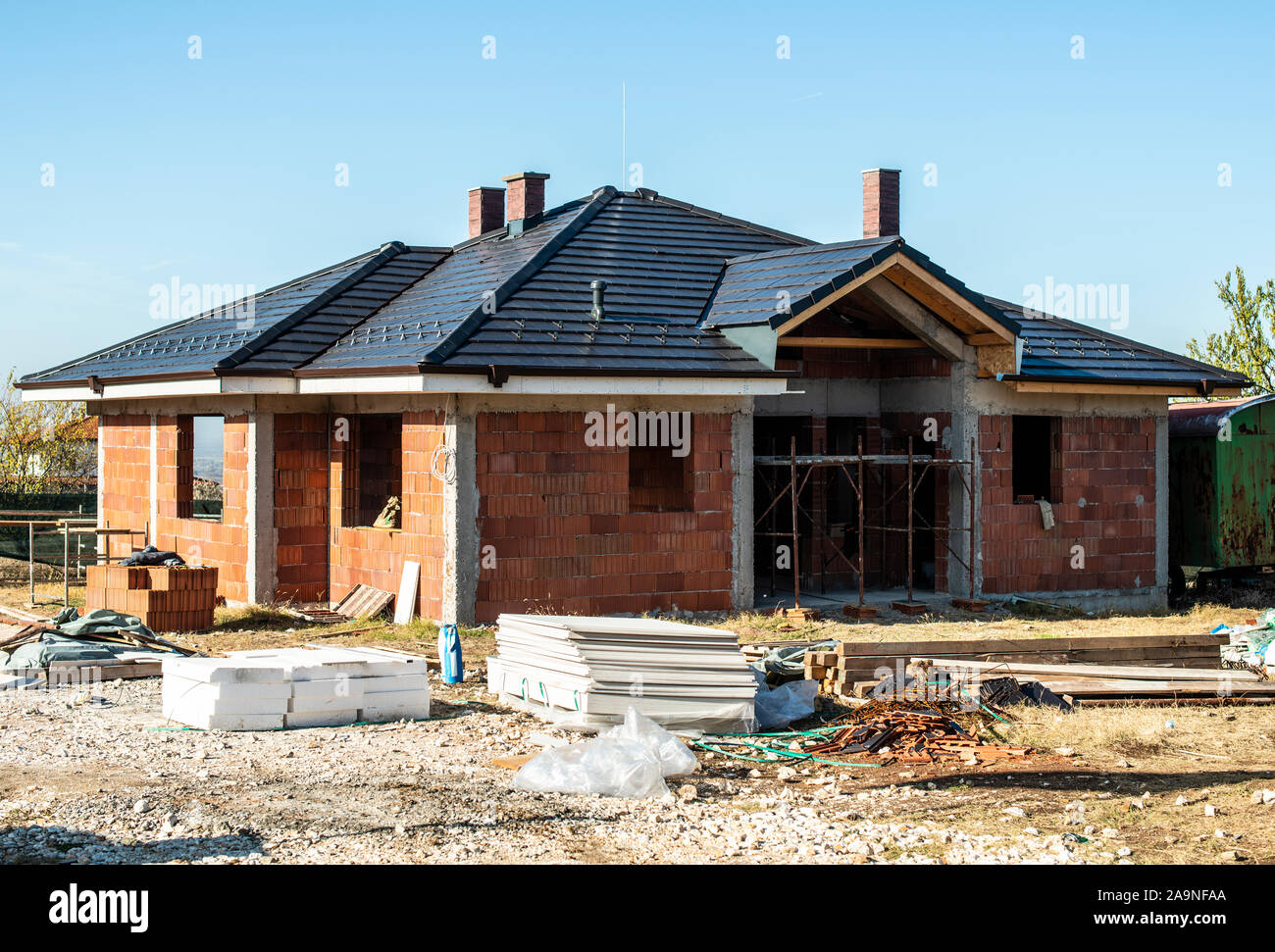 Building a new brick house with black roof. Small houses on construction site. Conception for new home, real estate and constructions. Stock Photo