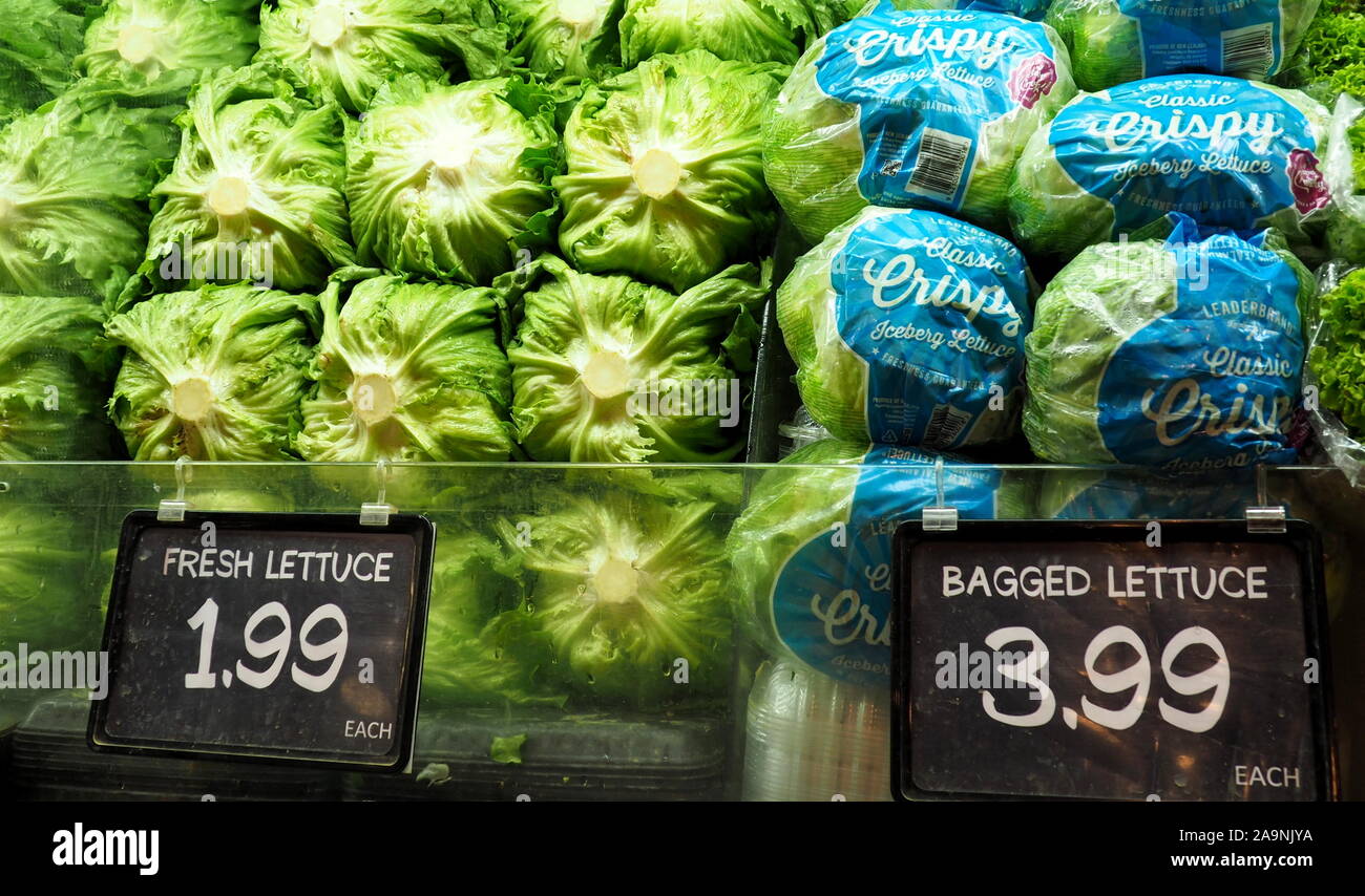 A supermarket stack of  iceberg lettuce, some bagged in plastic and doubled in price Stock Photo