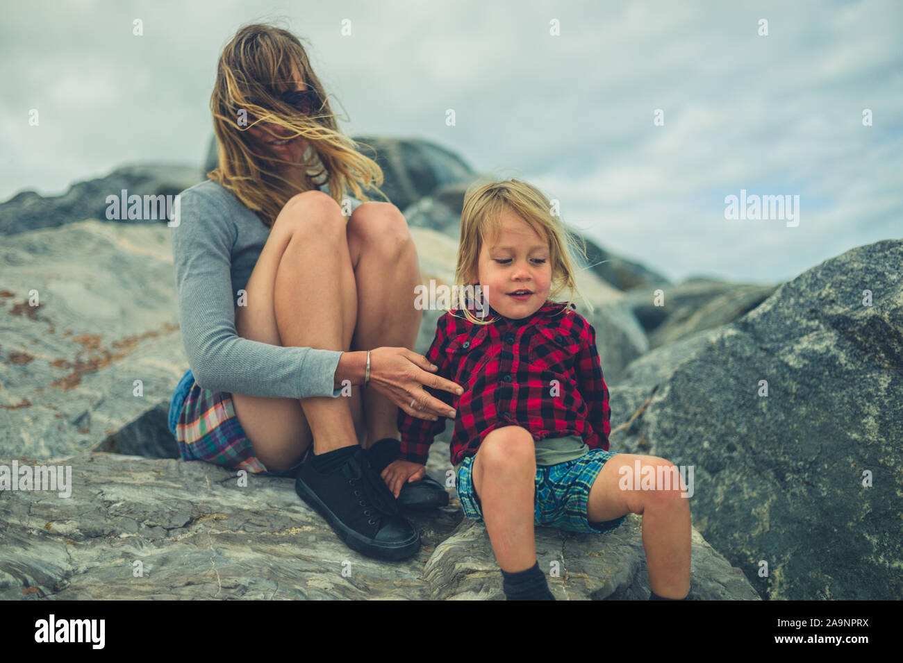 Mom With Rocks A young mother and her little toddler are sitting on some rocks Stock ...