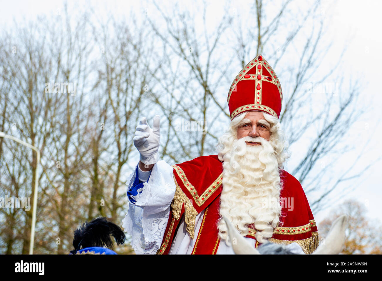 Sinterklaas waving to the public during the event.Like each year the first Saturday after November 11th, the red-and-white-clad Sinterklaas (St. Nicholas) arrives with great fanfare to several Dutch cities. In Nijmegen, the white-bearded legend makes his entrance into the city by sailing down the Waal River and following a route through the city. Along the route around 50 Anti-Zwarte Piet activists 'Kick Out Zwarte Piet' (KOZP) organized a protest against Sinterklaas' black-faced helpers. Also some people Pro Zwarte Piet showed up, the tension was palpable between the two sides. Stock Photo