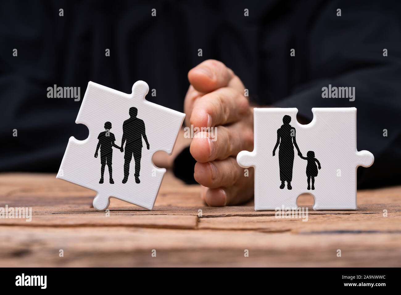 Man Dividing Two Jigsaw Puzzle Pieces With Hand Showing Divorce Concept Over Textured Wooden Desk Stock Photo