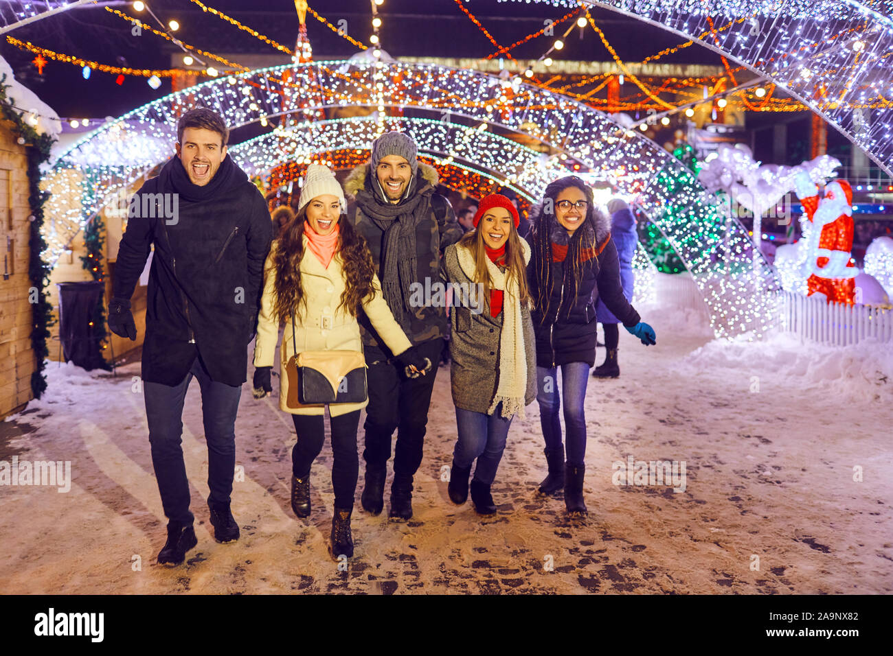 Friends have fun walking on Christmas streets at night. Stock Photo