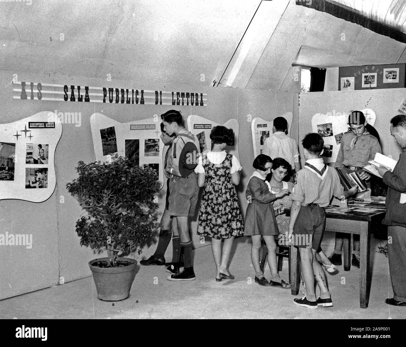 The exhibit was on the subject of 'the Amerian school.' Here children are interesting themselves in the photographic exhibit while others are asking the librarian (seated) questions about one of the most popular items, the 'Basic Science Education Series.' Stock Photo