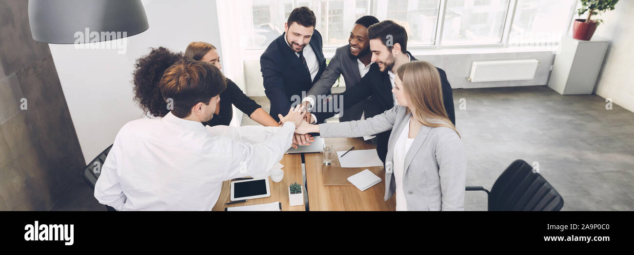 Young team joining hands involved in teambuilding activity Stock Photo