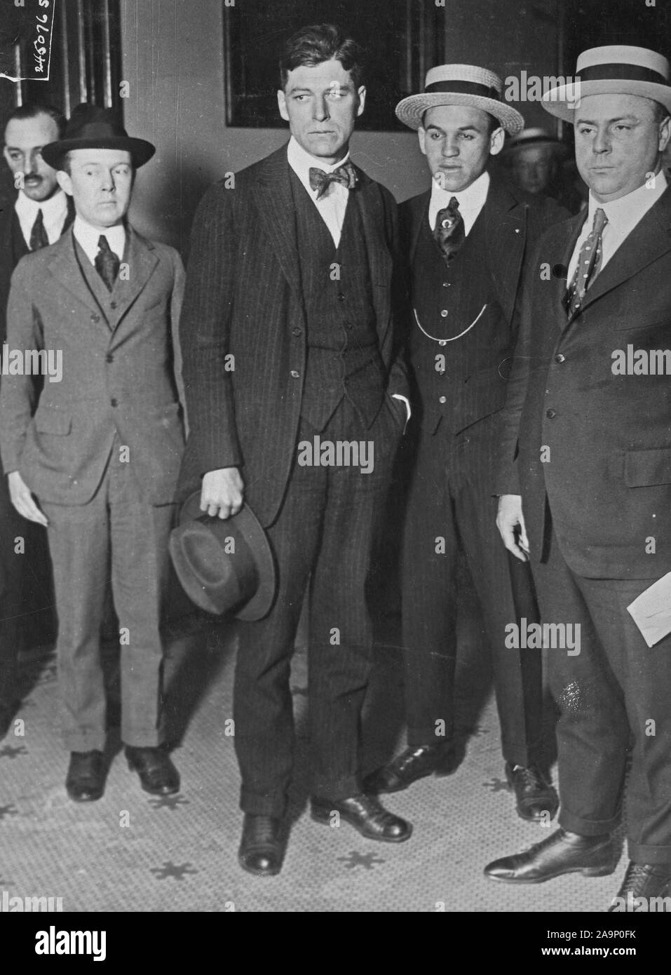 Jeremiah A. O'Leary (with hat off) charged with treason to the U.S., shortly after his arrival in New York City, on his way to the Federal building. O'Leary was captured by Federal agents on a chicken farm in the state of Washington where he fled to evade trial. Stock Photo