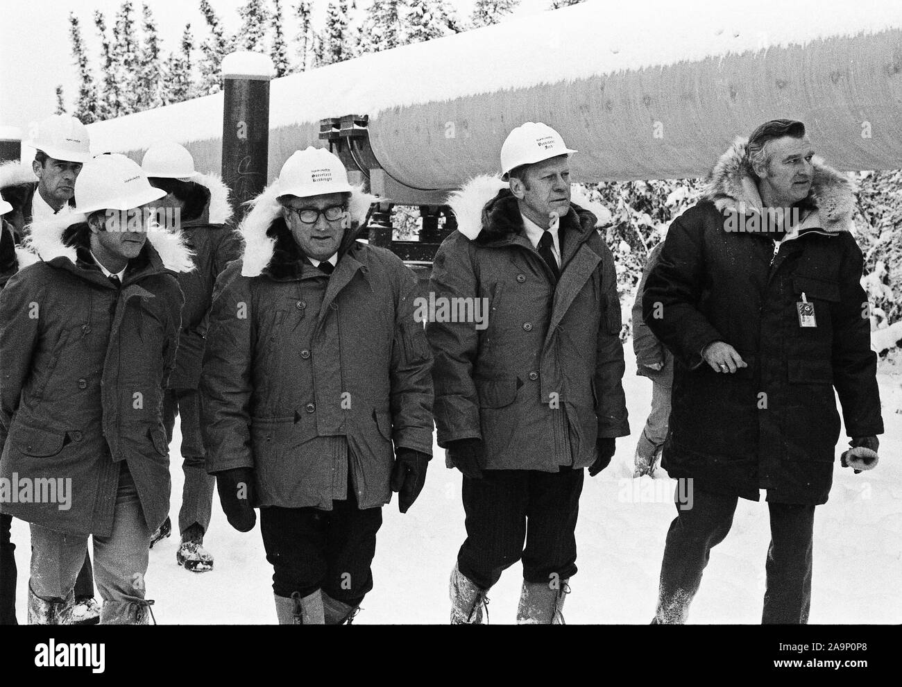 November 29 1975 – Alyeska Pipeline Service Company Pump Station #8 – Fairbanks, AK – Federal Energy Administration Administrator Frank Zarb, Secretary of State Henry Kissinger, and President Ford Touring the Trans-Alaska Pipeline wearing hard hats, arctic weather gear Stock Photo