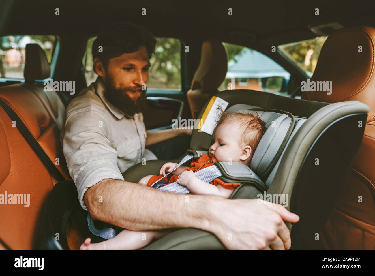 Father and baby in car child sitting in safety seat happy family