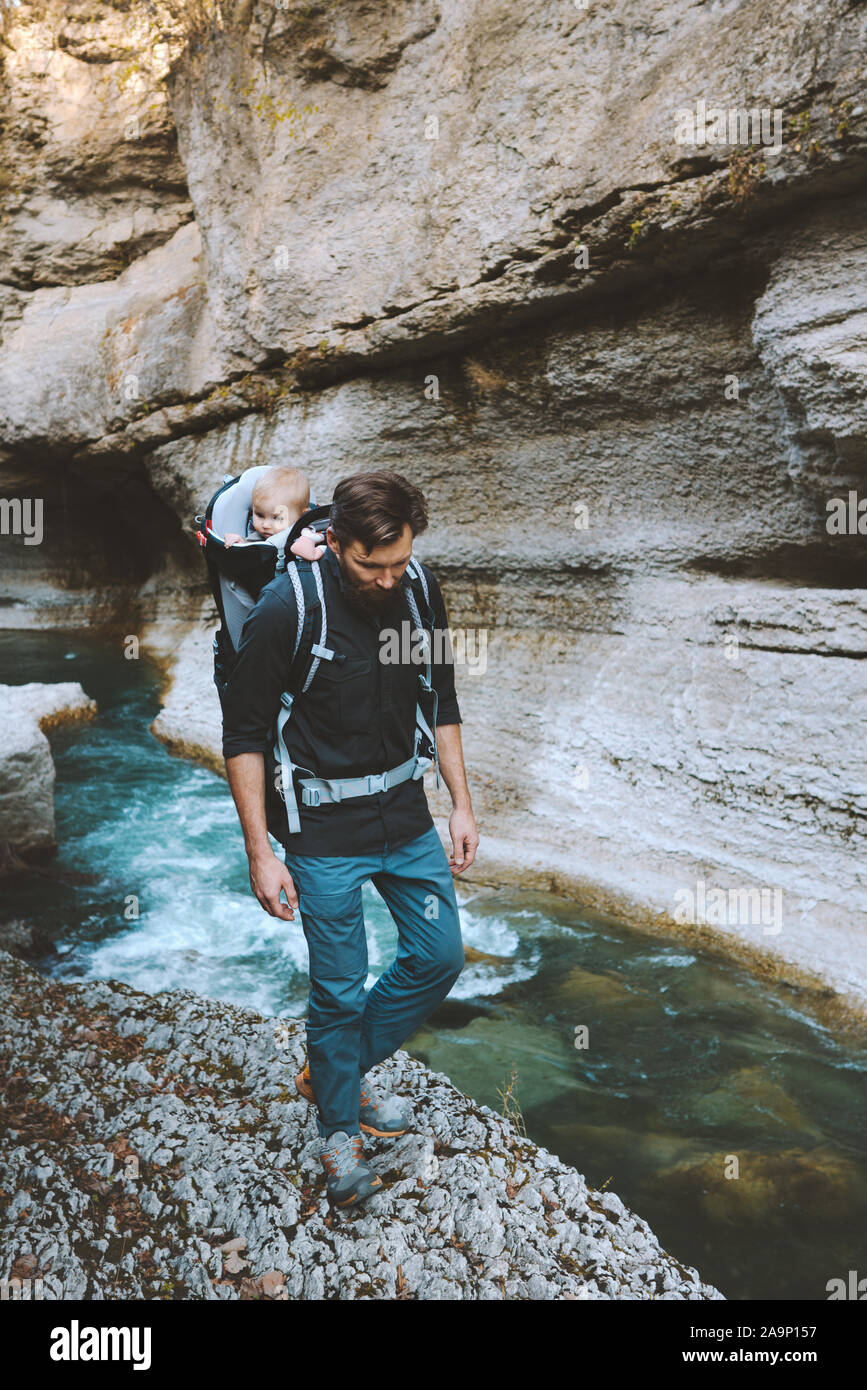 Father hiking in canyon with baby backpack carrier traveling adventure