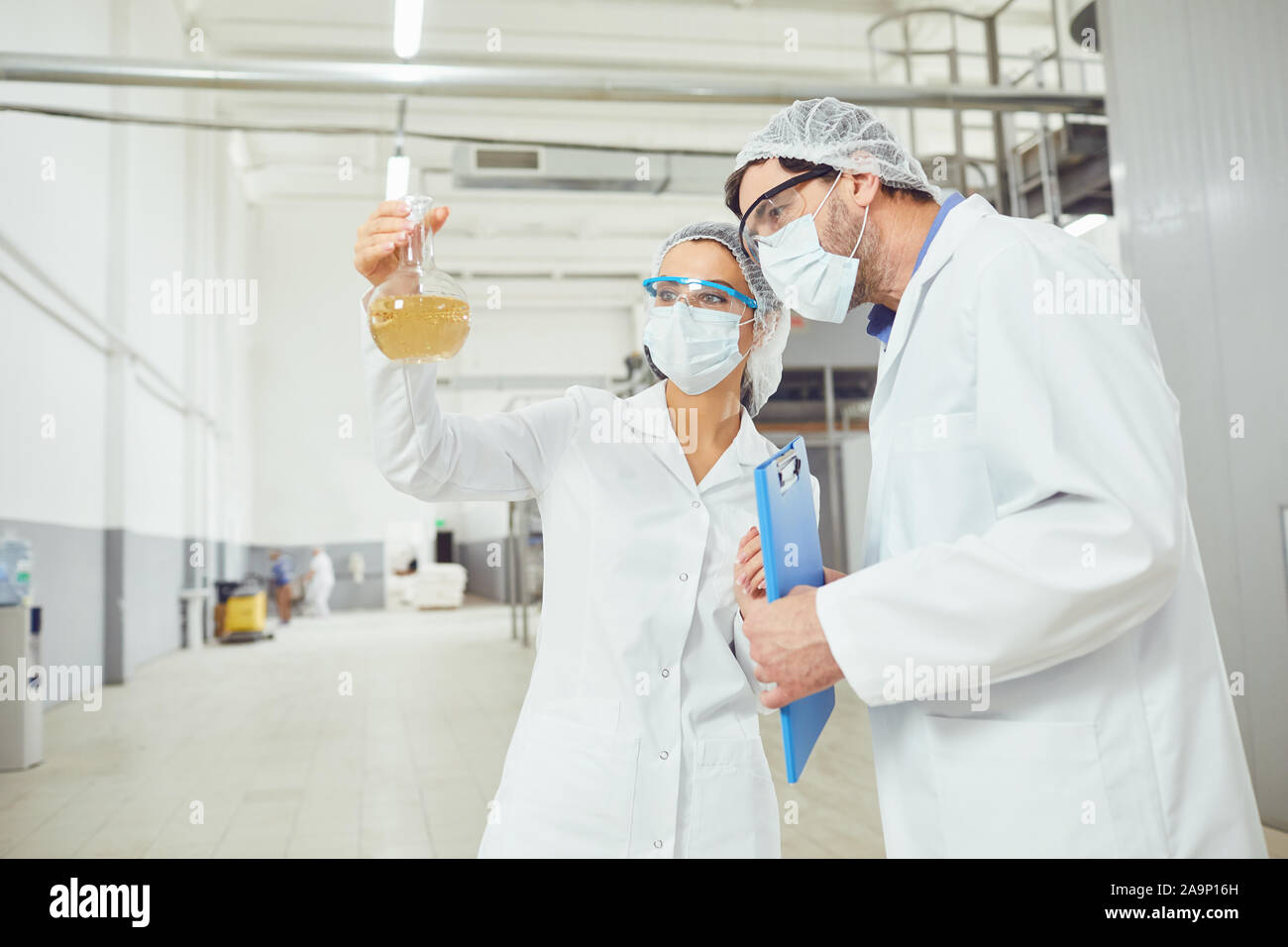 Technologist in masks and coats look at the liquid Stock Photo