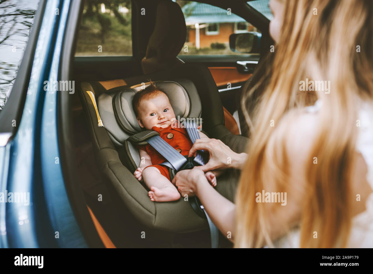 Mother putting baby in safety car seat family lifestyle child care transportation road trip vacations Stock Photo