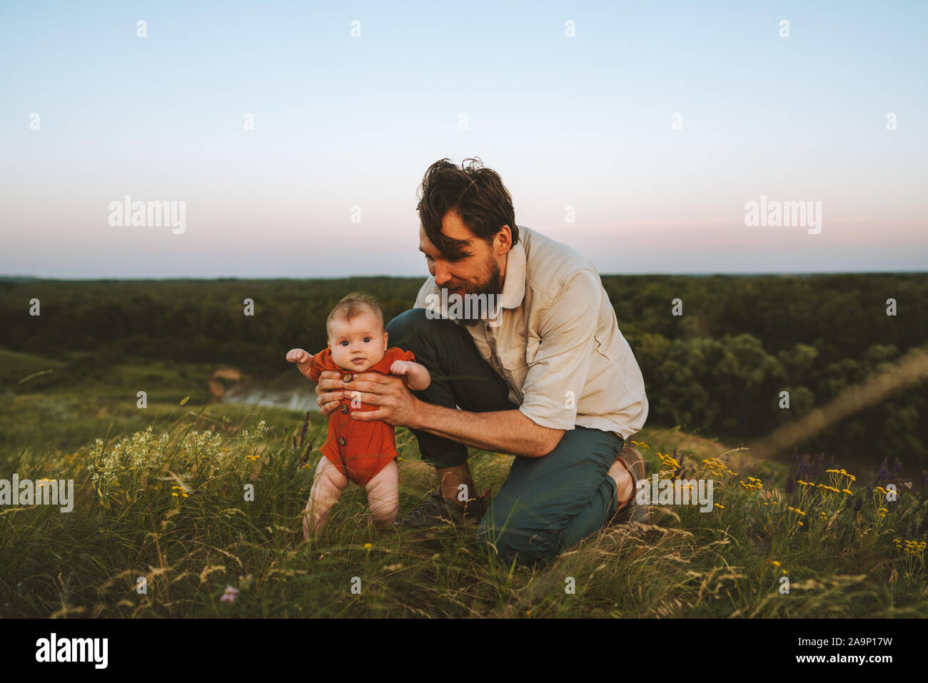 Baby and father outdoor happy family lifestyle dad and child walking together on grass meadow parenting childhood concept Fathers day holiday Stock Photo