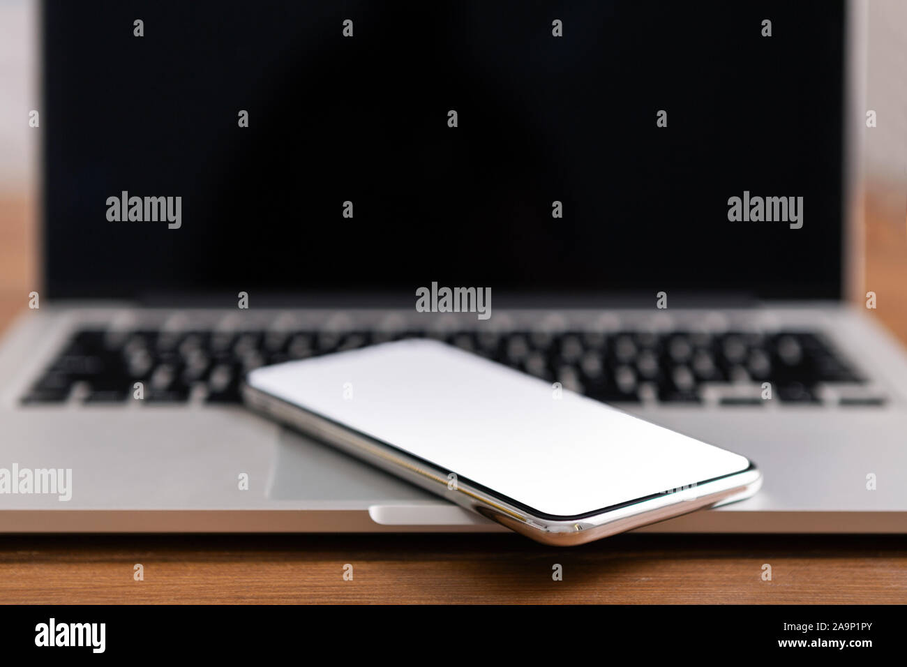 Smartphone with blank screen placed on laptop keyboard Stock Photo