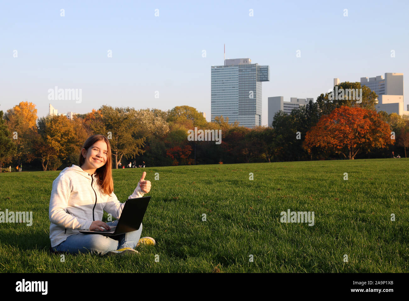 happy teenage girl with laptop and thumb up in Donaupark Vienna Stock Photo