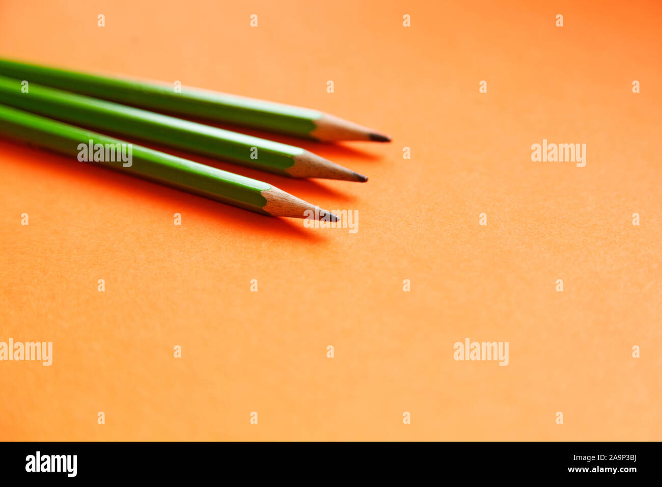 three green pencils lying on an orange background Stock Photo