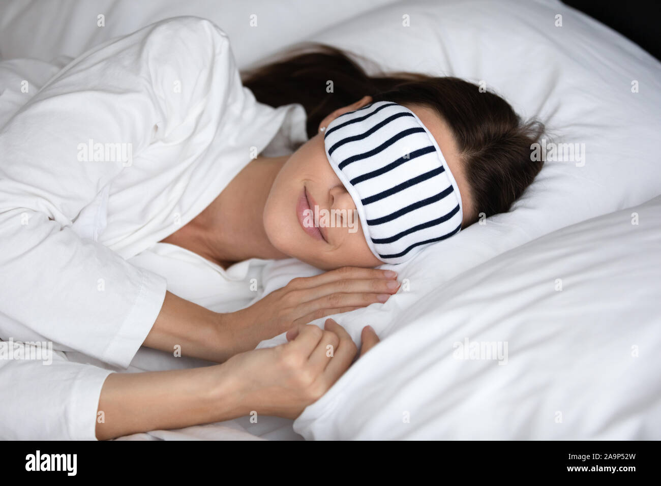 Calm serene woman wear sleeping mask resting in comfortable bed Stock Photo
