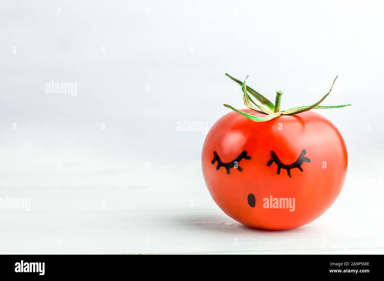 sleepy face painted on tomato. Dream. Copyspace Stock Photo