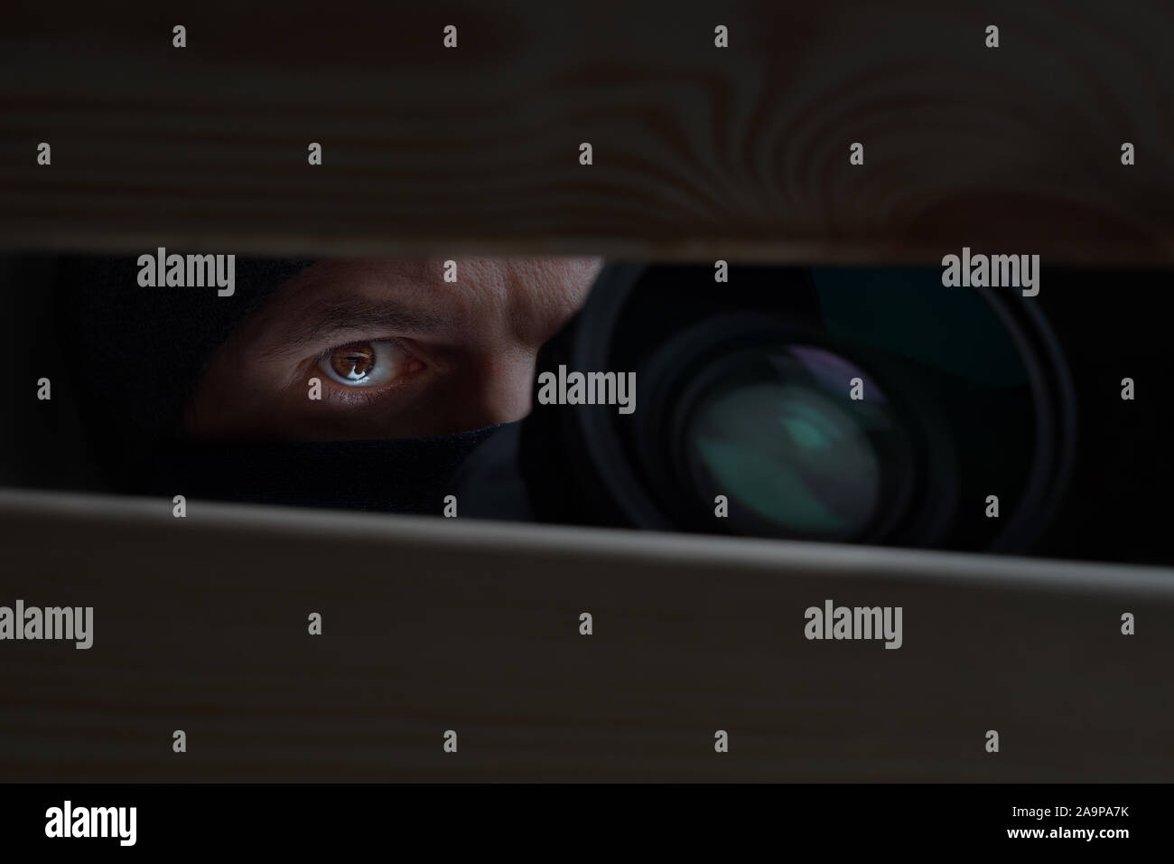 Male eye and camera close-up. Recording to a hidden camera. Private detective with camera looks at a cleft. Espionage background. The concept of eaves Stock Photo