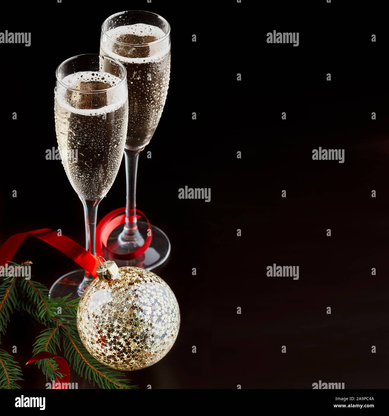 Christmas and New Years Eve celebration concept: two glasses with fizzy drink and a bottle of champagne in ice bucket with festive decorations Stock Photo