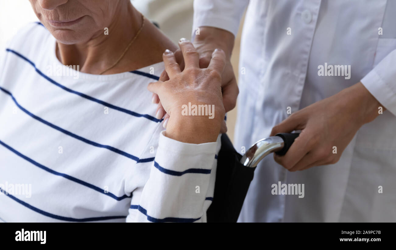 Female nurse carer supporting senior grandma on wheelchair, close up Stock Photo