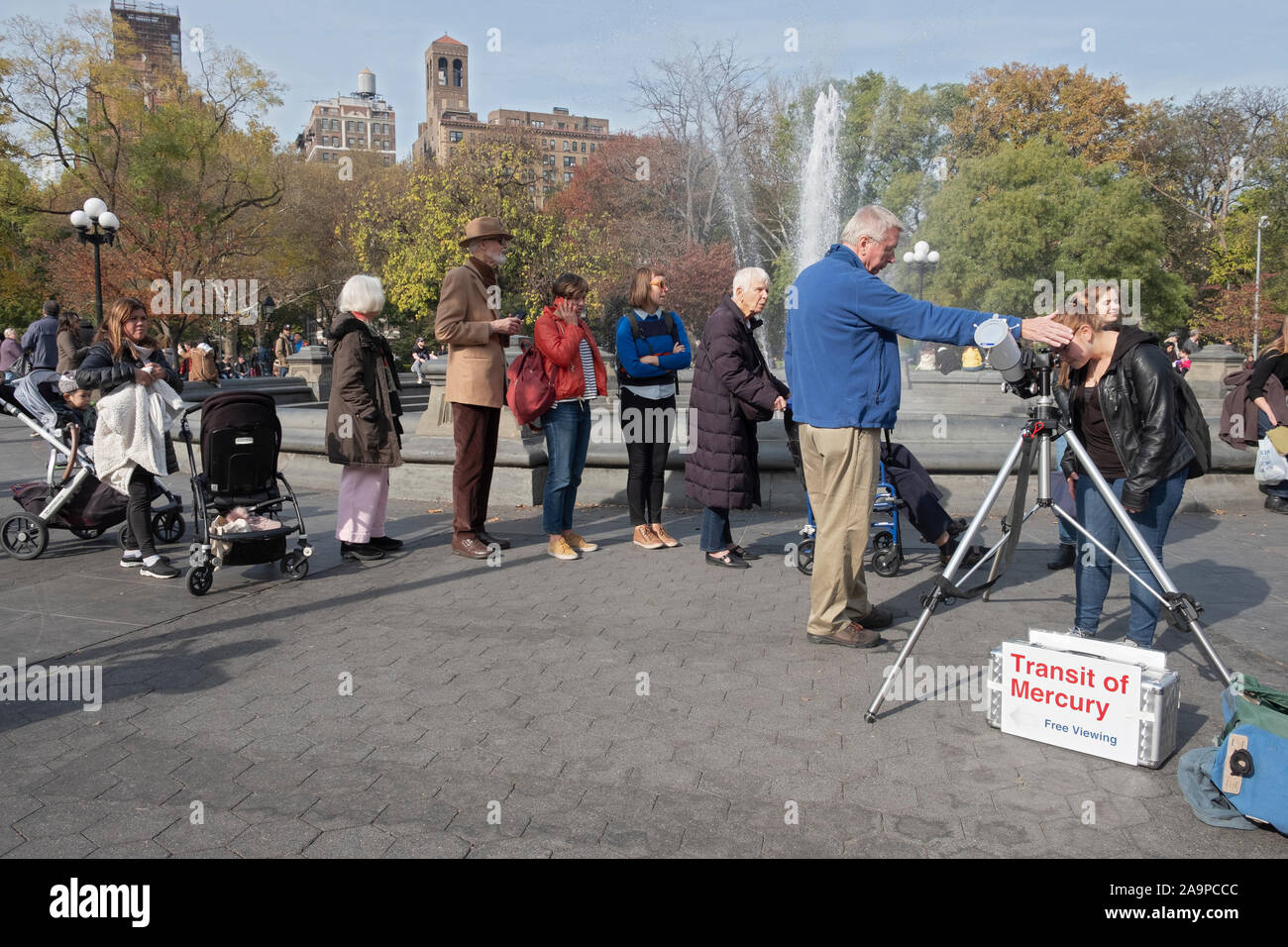 Curious people of all ages line up to look though a telescope & see the rare passing of Mercury between the earth & the sun. Stock Photo